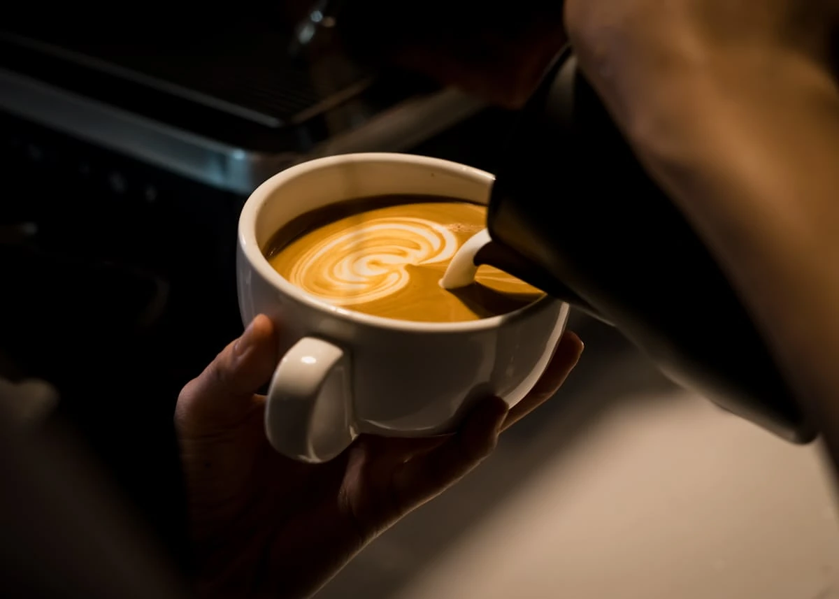 Kávéscsésze latte arttal egy kézben